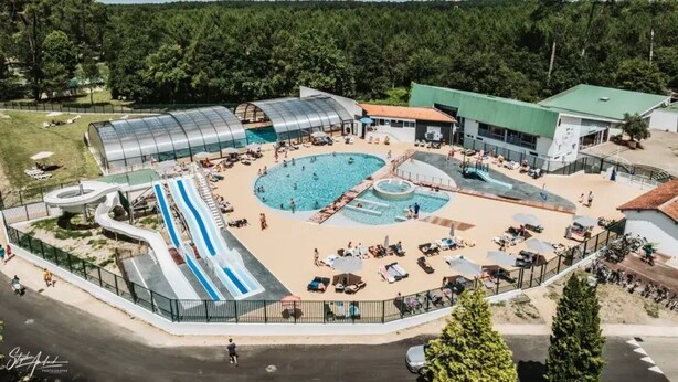 Ein Schwimmbadkomplex mit mehreren Becken, einer Wasserrutsche und einem überdachten Bereich.