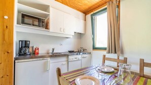 A compact kitchen with white cabinets, a microwave, a coffee maker, and a dining table set with plates and glasses.