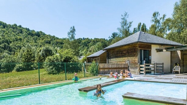 A swimming pool with a wooden deck and a building in the background.