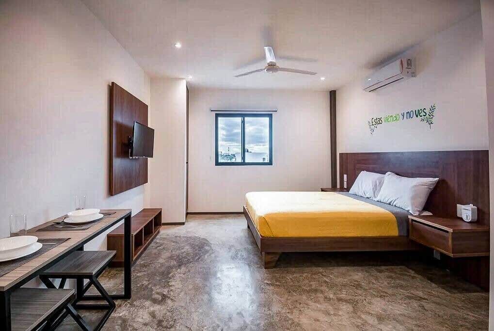 Una habitación de hotel moderna con cama, mesita de noche y escritorio con silla.
