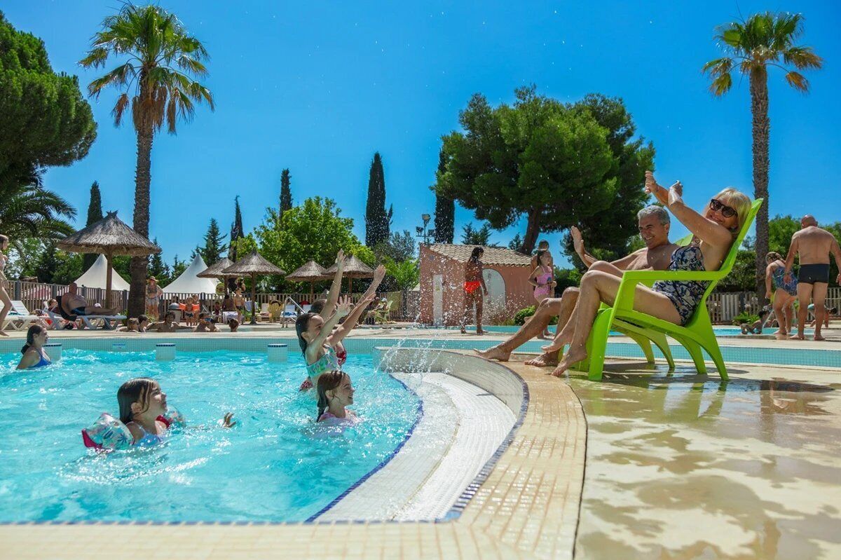 Un área de piscina con gente nadando y relajándose.