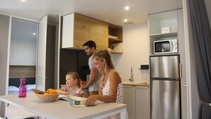 Una cucina moderna con mobili bianchi, un frigorifero in acciaio inossidabile e un forno a microonde sul piano di lavoro.
