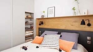 Una camera da letto con un letto, cuscini, una testiera, uno scaffale con vari oggetti e un armadio.
