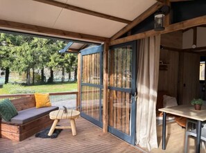 Une terrasse en bois avec un canapé, une petite table ronde et un coin repas comprenant une table et des chaises.