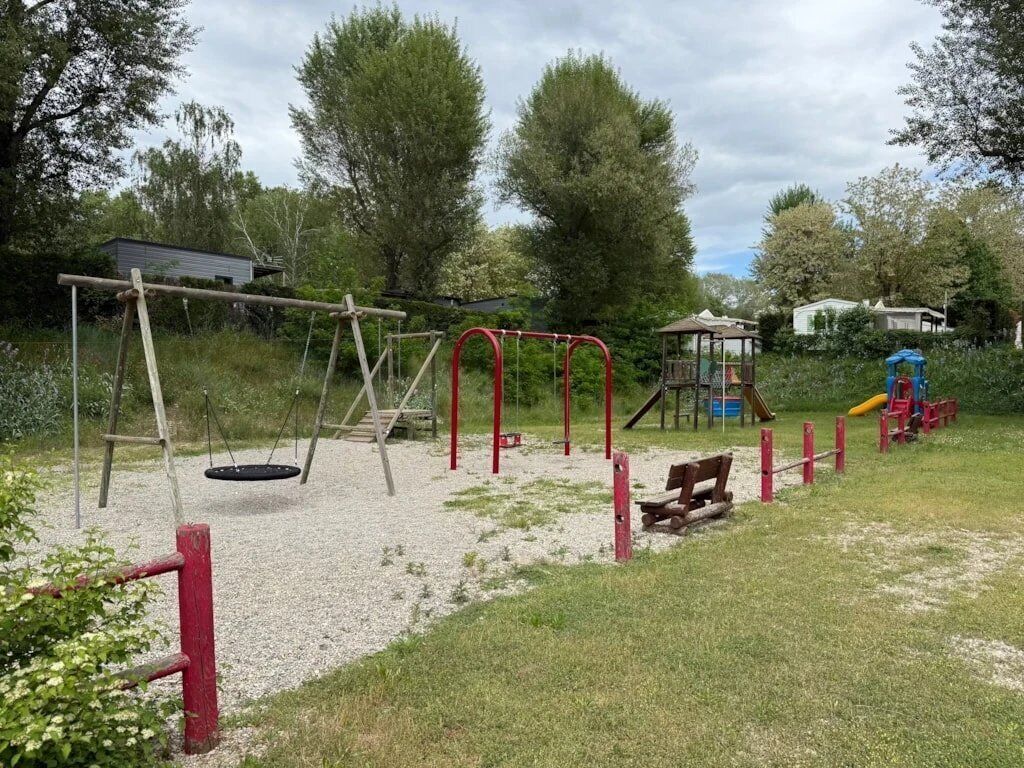 A playground with swings, a slide, and a small shelter.