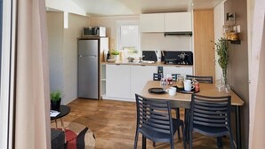 Et moderne køkken med spiseplads, med et træbord og stole, et køleskab og en mikrobølgeovn.