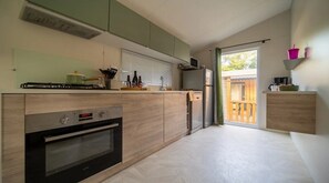 A modern kitchen with a built-in oven, a microwave, and a gas stove. - ZEcamping 4* animé piscine couverte pet friendly locatif TV BBQ clim (Laroque-des-Albères)