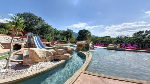 A water park with a slide, rock formations, and a pool area. - ZEcamping 4 étoiles animé piscine couverte locatif TV BBQ clim 32m2 (Laroque-des-Albères)