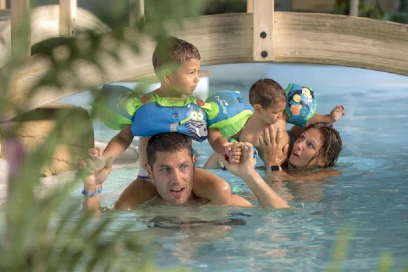 Ein Schwimmbecken mit einer Holzbrücke, klarem Wasser und Schwimmspielzeug.