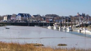 A marina with boats docked, a waterfront promenade, and residential buildings in the background. - ZEcamping 3* piscine chauffée jacuzzi locatif TV 18m2 2 pers (Grand-Laviers)