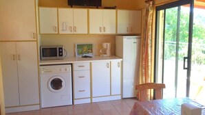 A compact kitchen with white cabinets, a microwave, a washing machine, and a refrigerator. - ZEcamping 4* familial piscine pet friendly chalet TV BBQ clim 45m2 (Saint-Rome-de-Tarn)