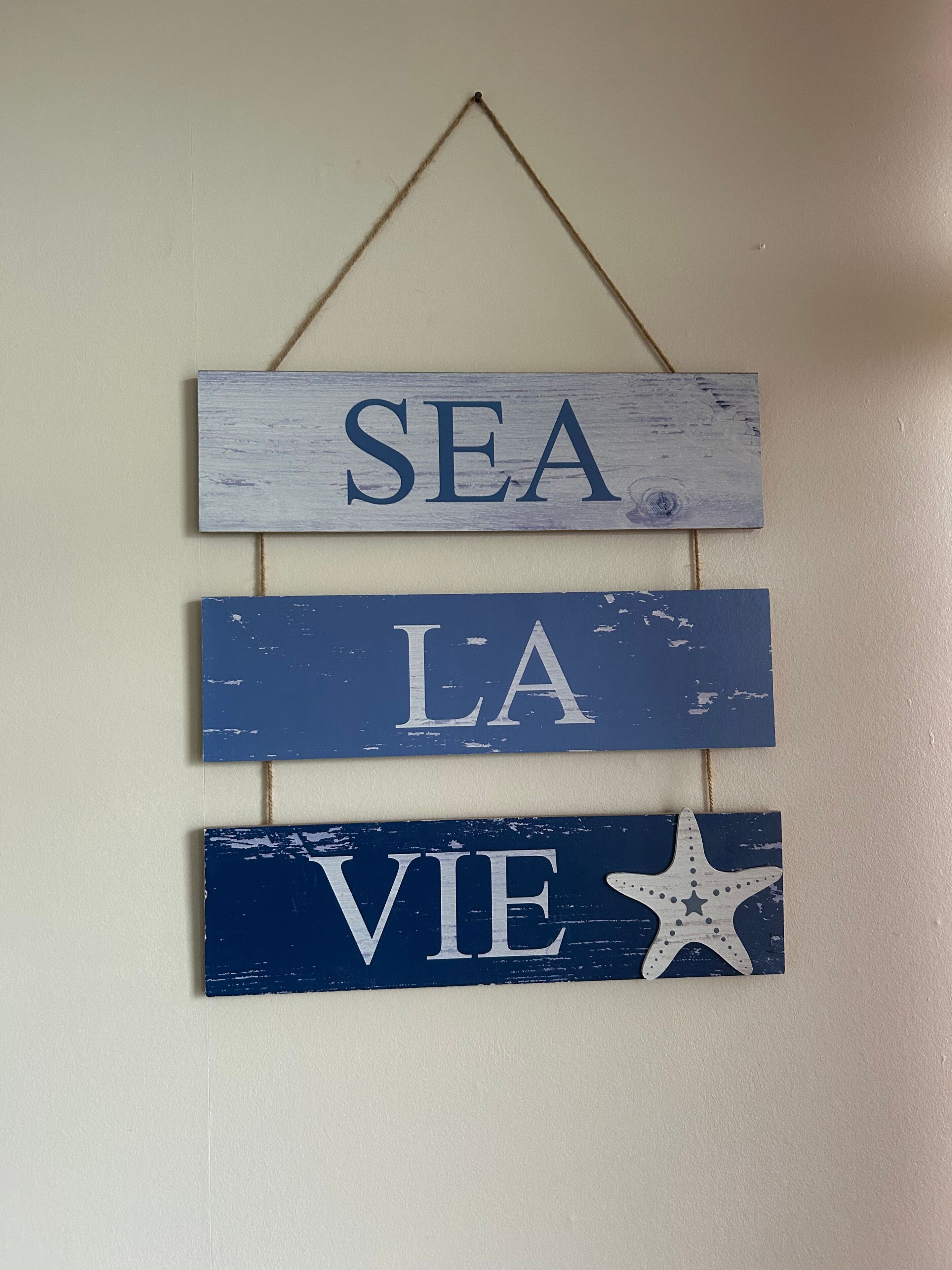 Una decoració penjada a la paret amb la frase 'SEA LA VIE' i una estrella.