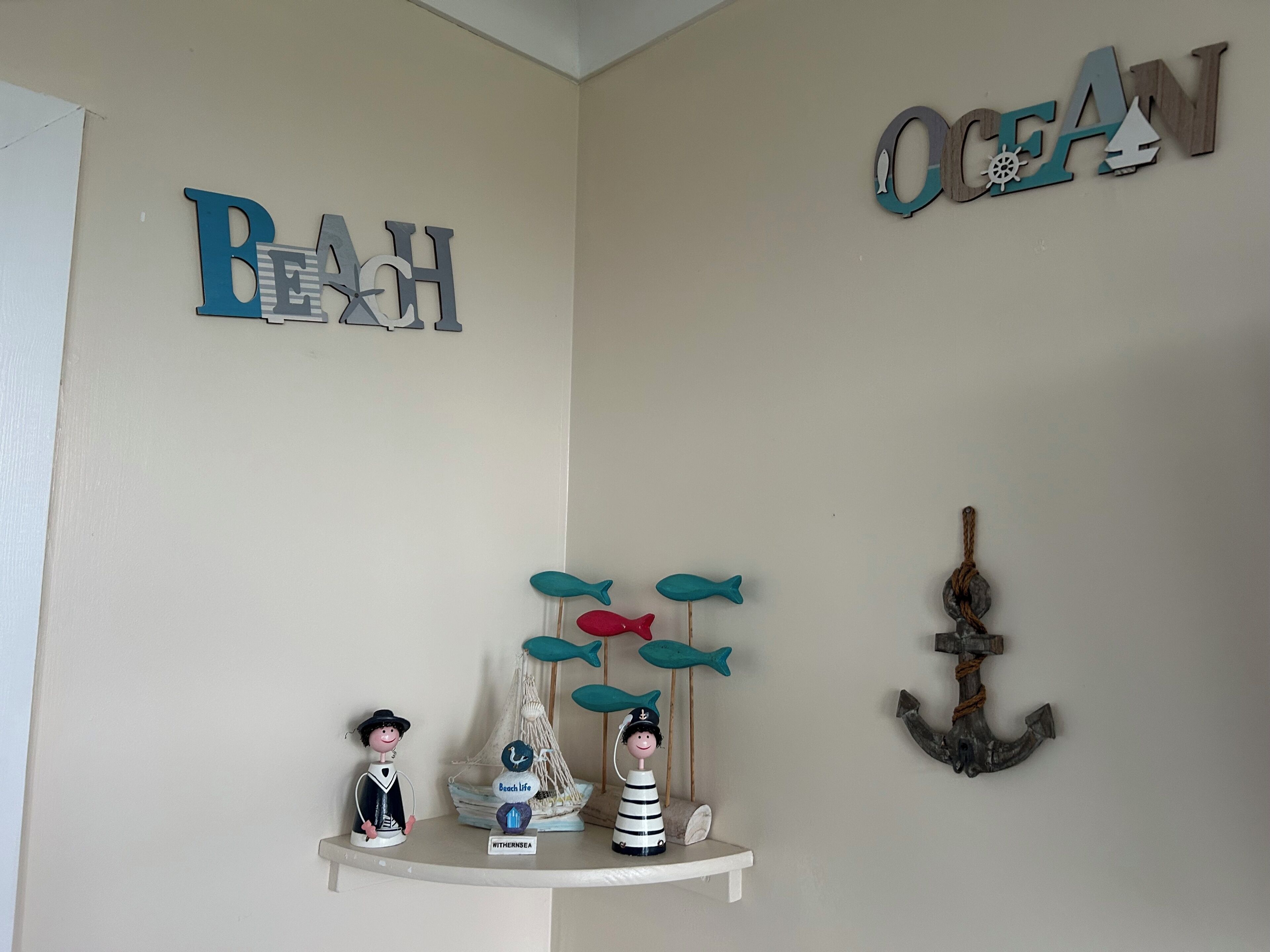 A shelf with nautical decorations including fish, a ship, and a sign that reads "Beach Life."