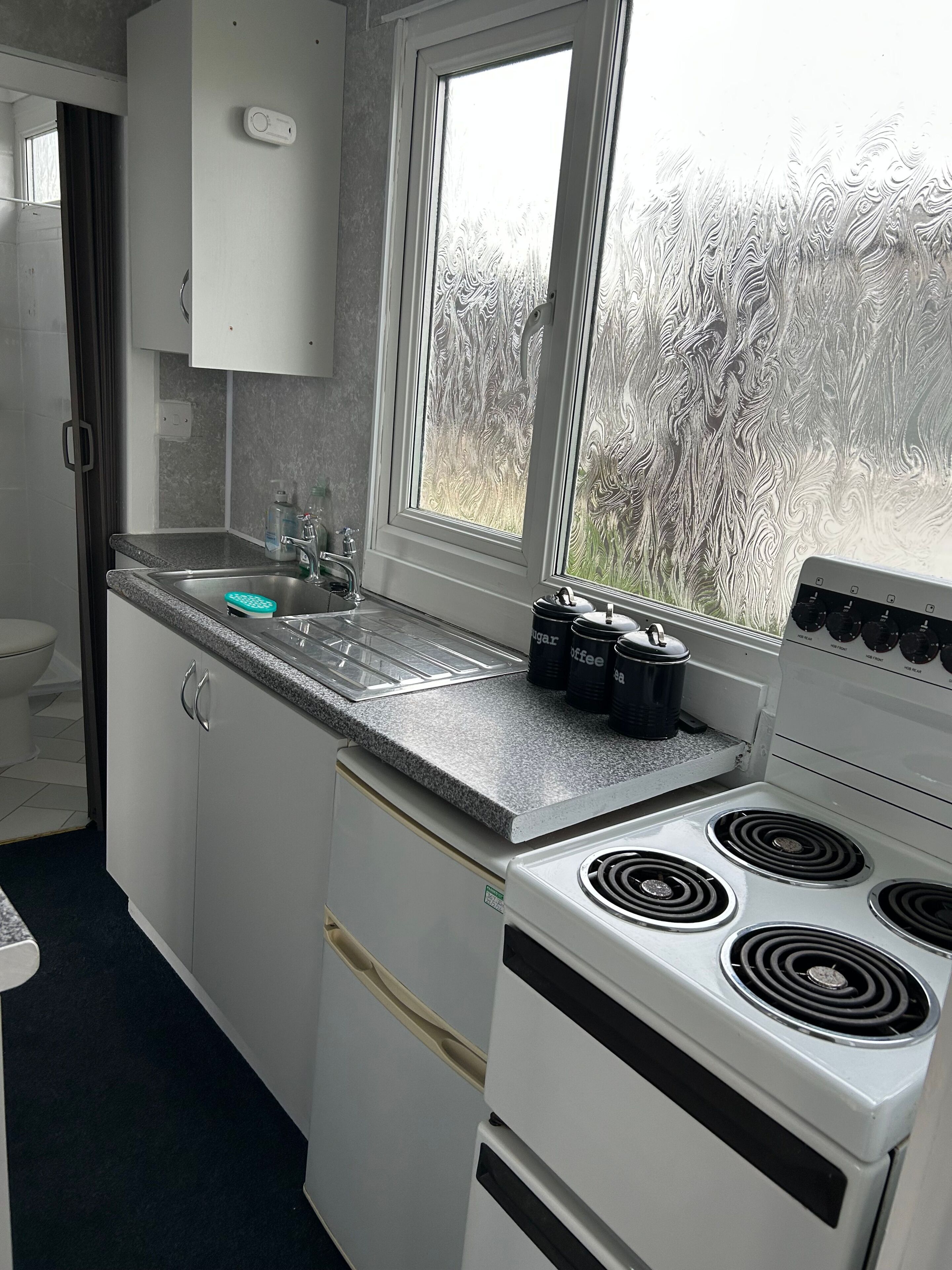 A compact kitchen with a stove, sink, and cabinets.