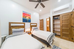 A bedroom with two beds, a ceiling fan, a painting, and wooden wardrobes. - CCV Quivira - Luxurious and Beautiful 2BR w/ Ocean Views and Golf! (Cabo San Lucas)