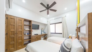 Een slaapkamer met twee bedden, een bureau, een televisie en een kledingkast.