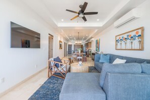 Ein geräumiger Wohnbereich mit Deckenventilator, einer großen Couch, einem Esstisch und einer Küche im Hintergrund.