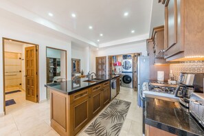 Une cuisine moderne avec des meubles en bois, un îlot central, un four encastré et un four à micro-ondes.