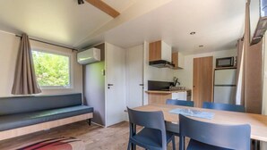A compact kitchen with a microwave, stove, and sink. - ZEcamping 3* animé piscine chauffée locatif TV LV clim 35m2 (Hauterives)