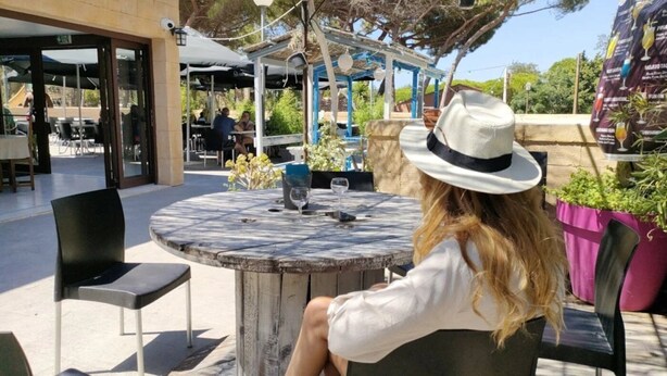 A person seated at an outdoor table with a drink and a glass, surrounded by chairs and a covered seating area. - ZEcamping 3 étoiles 200m plage animaux acceptés locatif TV clim 26m2 (Hyères)