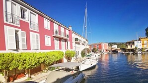 A canal with boats, a red building with white shutters, and a clear blue sky. - ZEcamping 3 étoiles 200m plage animaux acceptés locatif TV clim 26m2 (Hyères)