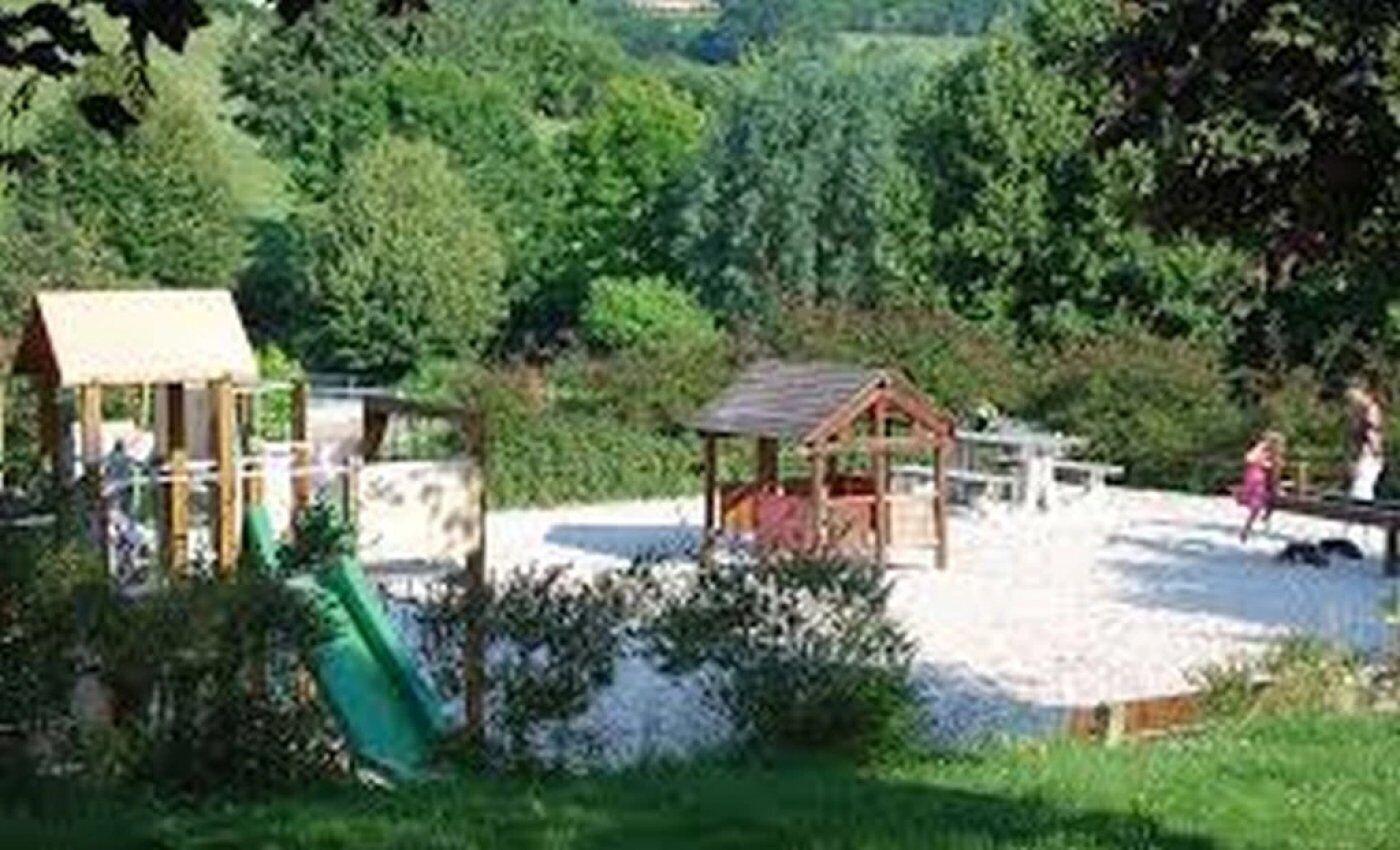 Un parque infantil con un tobogán y una pequeña estructura de madera.