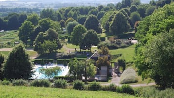 A pool surrounded by lush greenery and a small building, likely a lodge or resort.