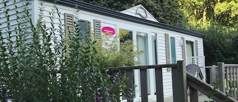 En hvid campingvogn med en træterrasse og et pink skilt, der angiver en sauna.