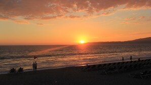 A beach with a sunset, people walking, and beach chairs. - Bliss at the beach (Nuevo Nayarit)