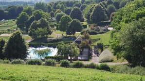 Ländliche Landschaft mit Schwimmbad, einem Haus und umgebender Bepflanzung.