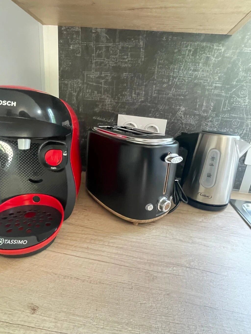 A kitchen with a Bosch mixer, a Cobalt toaster, and a Cobalt coffee maker on a wooden countertop.