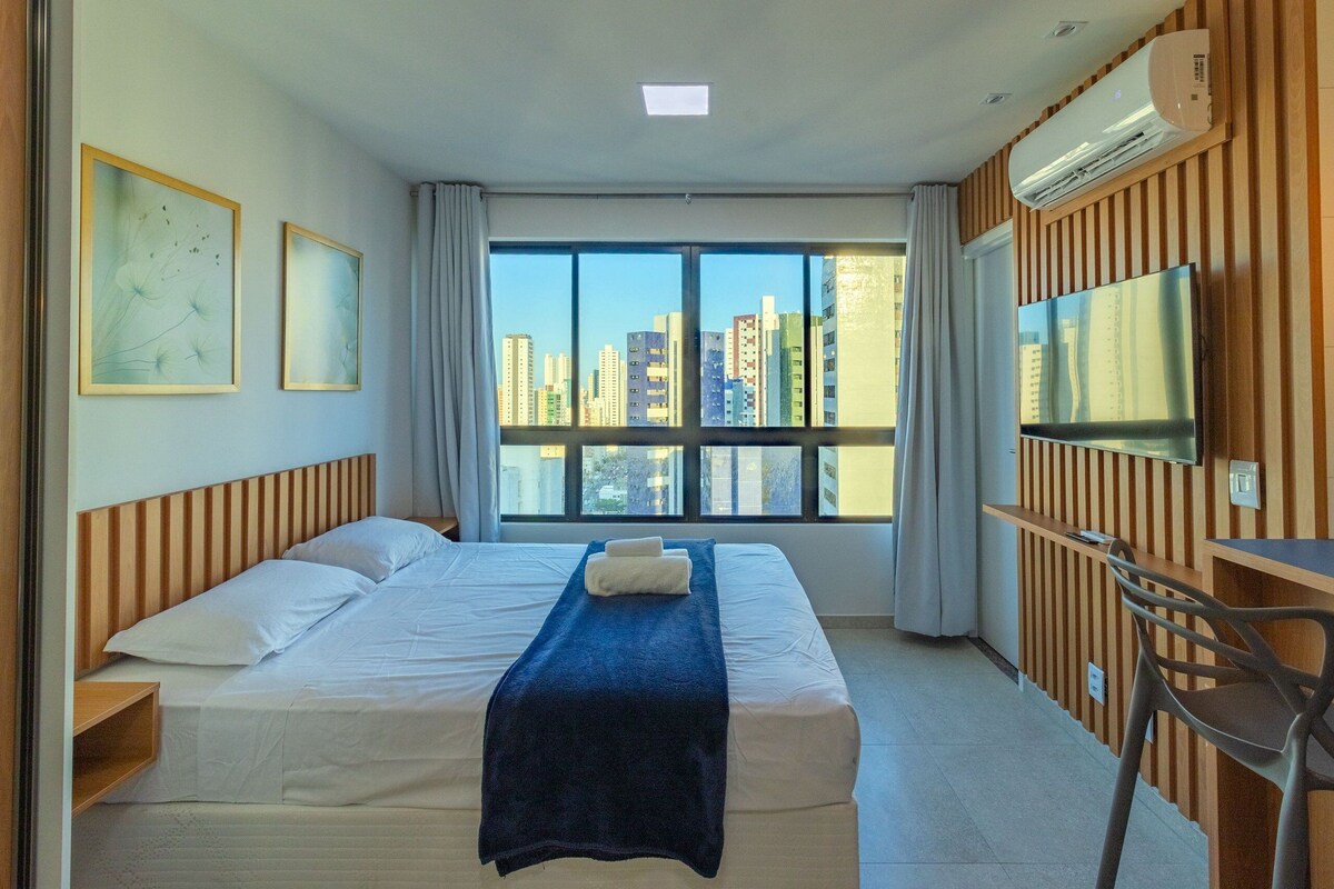Ein Hotelzimmer mit einem großen Bett, einem Fernseher und Blick auf die Skyline der Stadt.
