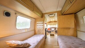 A compact RV interior with two beds, a kitchenette, and a seating area. - ZEcamping 3 étoiles familial piscine chauffée locatif 16m2 2 pers (Hauterives)