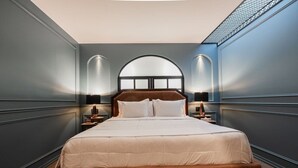 A modern bedroom with a large bed, two bedside tables, and a unique arched window. - King Bed & Private Soaking Tub (Ciudad de México)