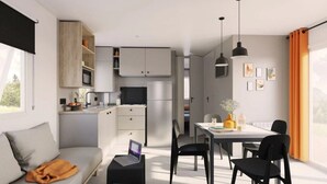 Een moderne, compacte woonruimte met kitchenette, eethoek en een bank met een laptop op een bijzettafeltje.
