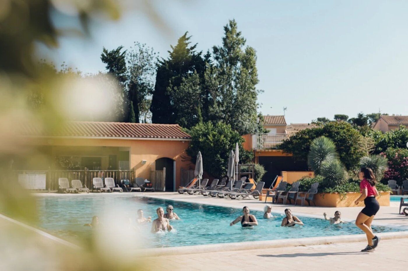 Ein Poolbereich mit Liegestühlen und einem Gebäude im Hintergrund.