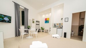 A modern hotel room with a bed, a desk, and a kitchenette. - Valguarnera Studio Apartaments (Palermo)