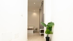 A narrow hallway with a potted plant, a bed, and a small table. - Valguarnera Studio Apartaments (Palermo)