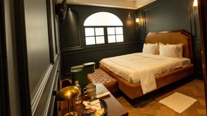 Una camera d'albergo con un letto, comodino, lampada e una finestra vista.