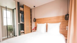 Ein Schlafzimmer mit einem hölzernen Kopfteil, einem großen Bett, einem Schrank mit Rattanverkleidung und einer Pendelleuchte.