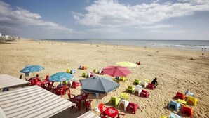 A beach with umbrellas, chairs, and tables arranged for sunbathing. - ZEcamping 4* espace aquatique animations locatif TV LV clim 32m2 (Soullans)