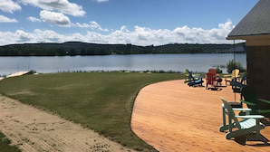 A wooden deck with outdoor furniture, a lake view, and a building in the background. - Summer Ready: Private 4BR Lakefront Cottage in Barry's Bay (Barry`s Bay)