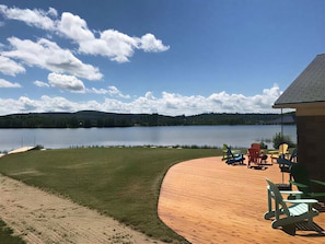 A wooden deck with outdoor furniture, a lake view, and a building in the background.