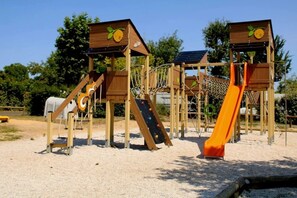 Ein Spielplatz mit Klettergerüsten, Rutschen und Sandboden.