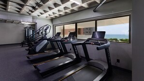 A gym with treadmills, a weight machine, and a large window offering a view of the ocean. - Beach Class #1104 - Quadruplo por Carpediem (Recife)