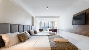 A modern hotel room with a large bed, a TV mounted on the wall, and a view of the sea through the window. - Beach Class #1104 - Quadruplo por Carpediem (Recife)