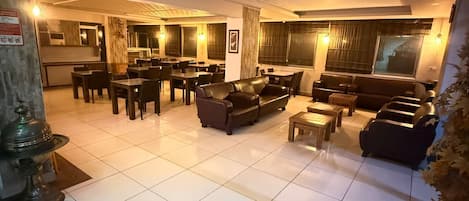 Un vestíbulo de hotel con zona de comedor, sofás y suelo de baldosas.