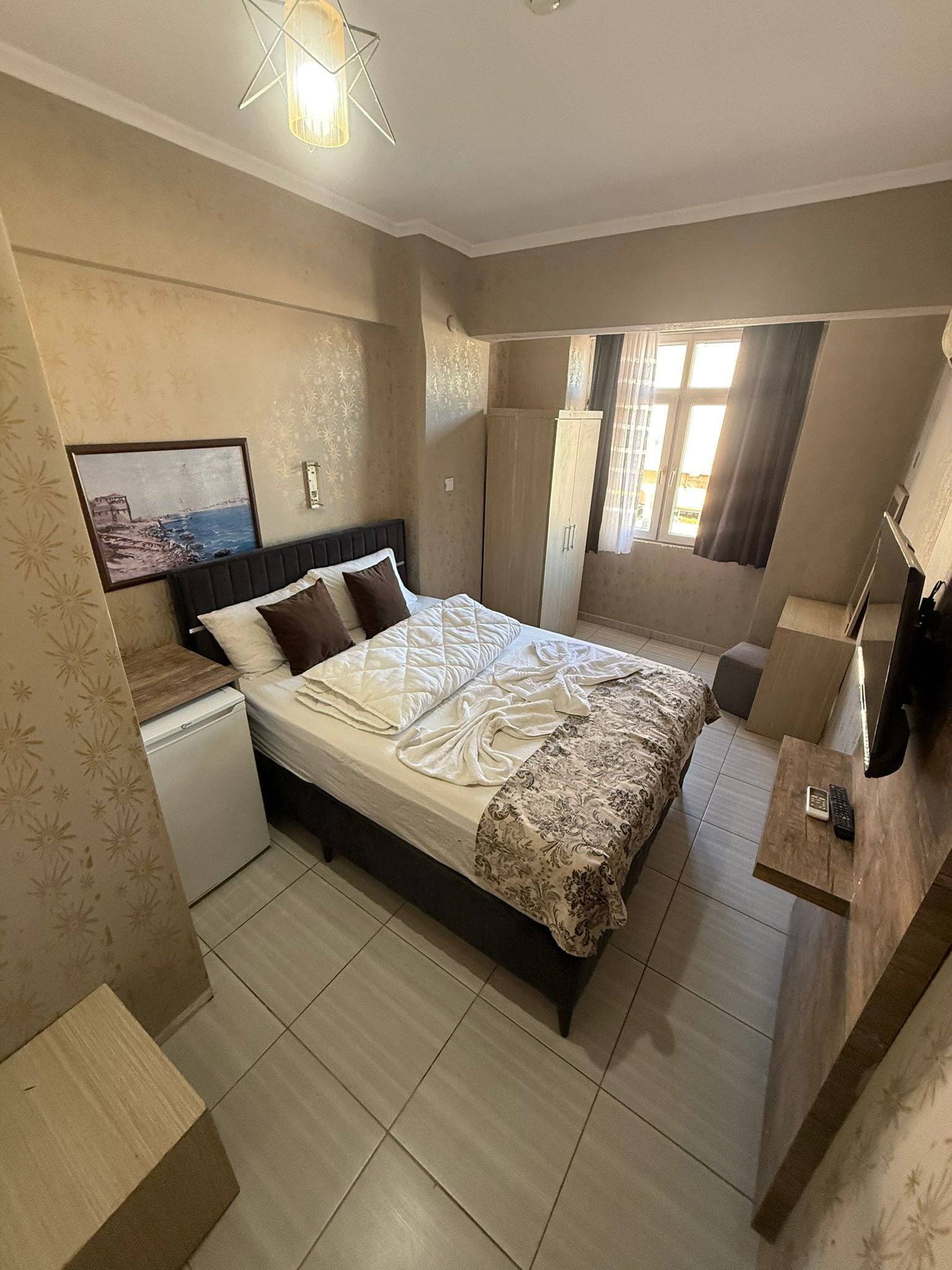 A bedroom with a bed, a wardrobe, a small desk, and a television.