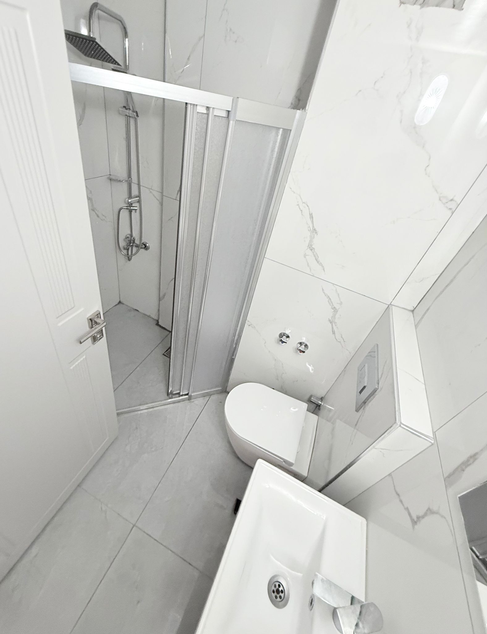A modern bathroom with a shower, toilet, and sink.