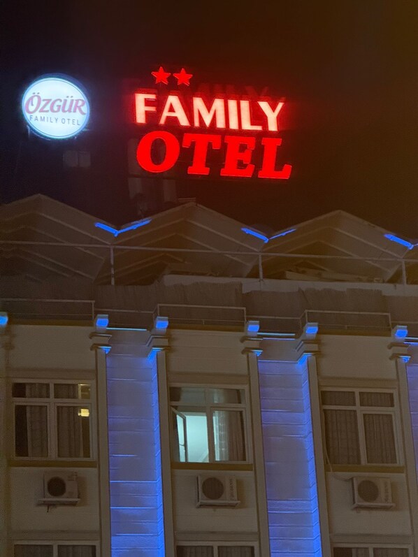 A building with a sign that reads 'FAMILY HOTEL' and 'ÖZGÜR FAMILY HOTEL' in illuminated letters. - Özgür Family Otel (Antalya)